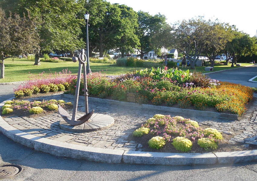 Anchor monument surrounded by colorful flower beds in a waterfront park